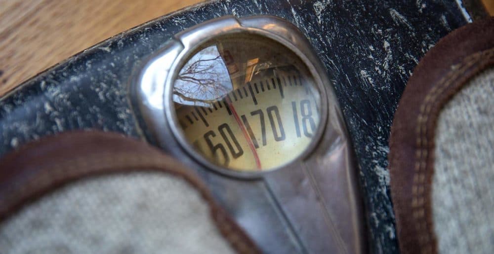 A person stands on an old body weight scale. (Robin Lubbock/WBUR)