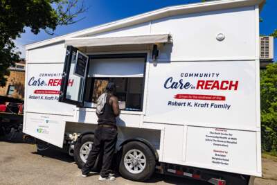 A man stands at the window of the Brockton Neighborhood Community Health Center mobile addiction outreach unit, which was funded in 2022 as part of the HEALing Communities study. (Jesse Costa/WBUR)