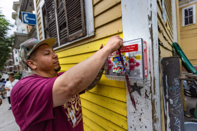 New North Citizens Council outreach worker Carlos Matias checks a NaloxBox Opioid Rescue Kit located on High Street in downtown Springfield, an overdose hotspot. (Jesse Costa/WBUR)