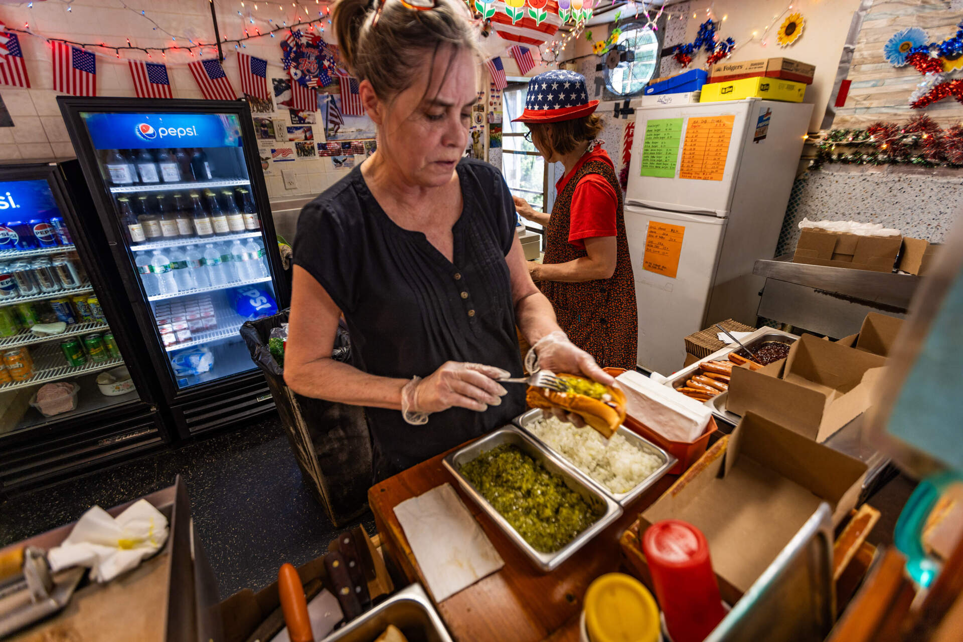 Wendy Harmon dresses a hot dog with onions and pickles at Hot Dog Annie’s in Leicester, Mass. (Jesse Costa/WBUR)