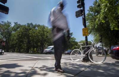 A pedestrian walks past the ghost bike memorial site where a cyclist was killed in Boston in 2017. (Jesse Costa/WBUR)