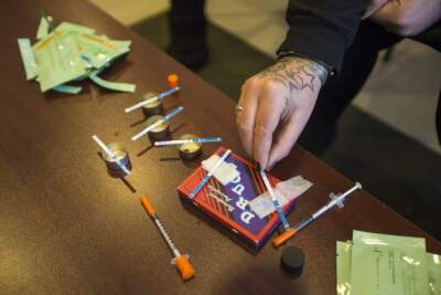 An opioid harm reduction worker demonstrates how to test empty heroin bags for fentanyl. (Jesse Costa/WBUR)