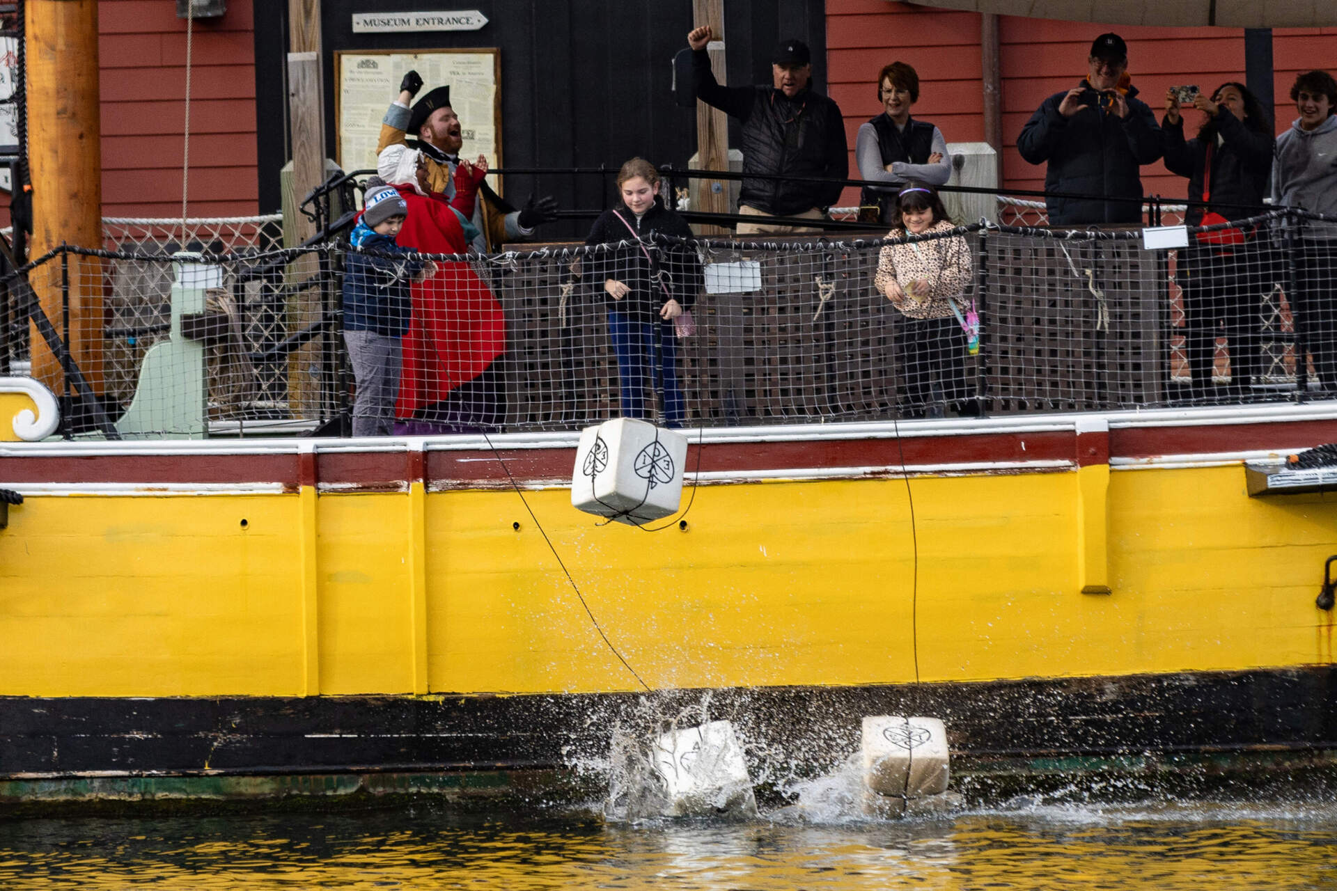 Crates splash into the Fort Point Channel after children toss them overboard during a visit to the Boston Tea Party Museum. (Jesse Costa/WBUR)