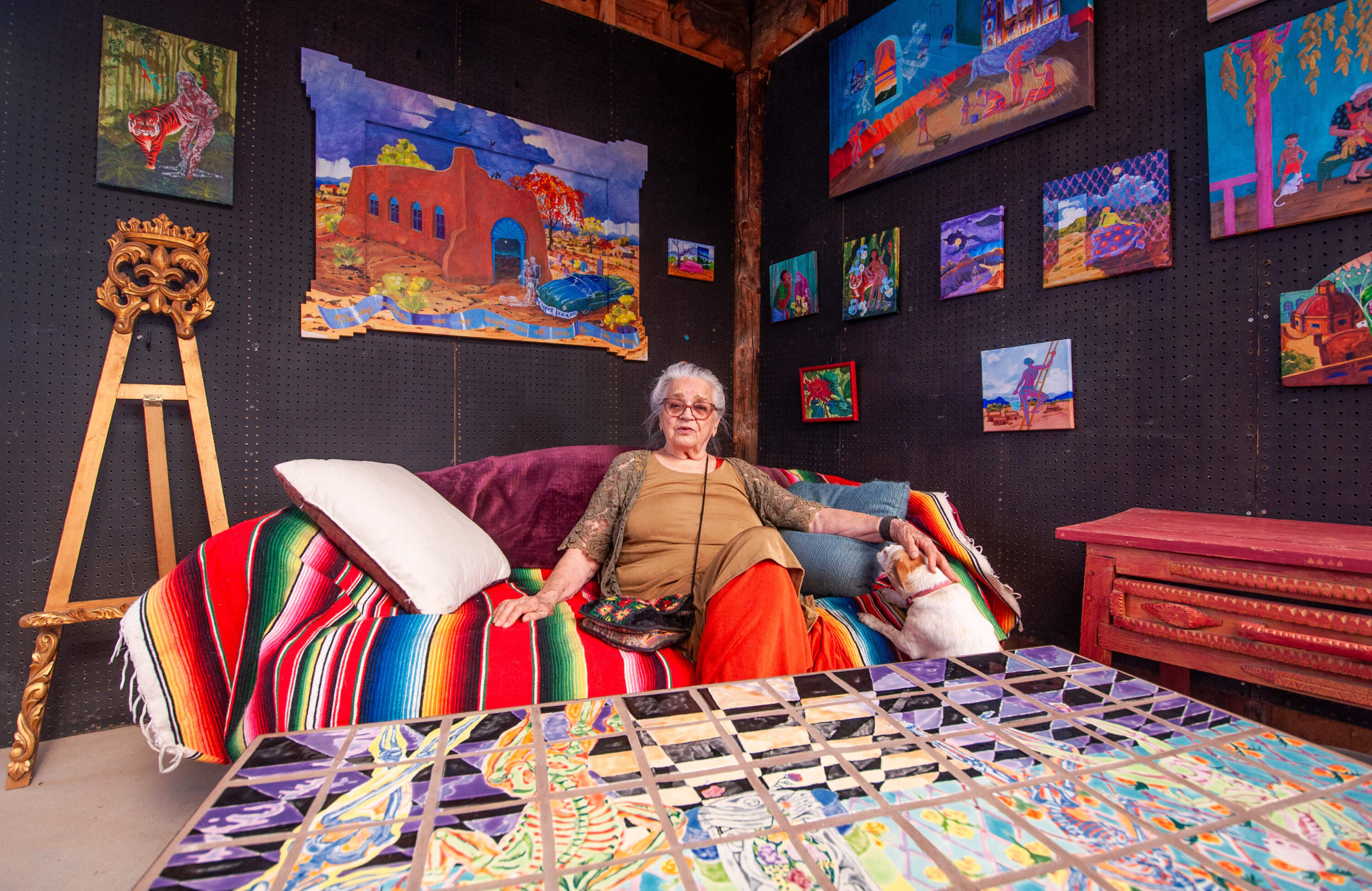 Anita Otilia Rodríguez at her home in Taos, New Mexico with some of her paintings. (Chris Bentley/Here &amp; Now)