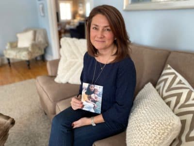 Leigh Small, 48, holds an old picture of herself next to her biological mother. (Andrea Asuaje/WBUR)