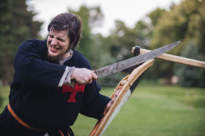 A man dressed in medieval clothing fights with a shield and a sword in the forest. (Getty/FluxFactory)