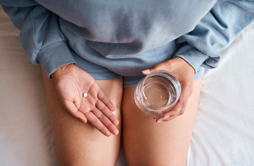 A woman holds a pill and a glass of water. (Getty Images)